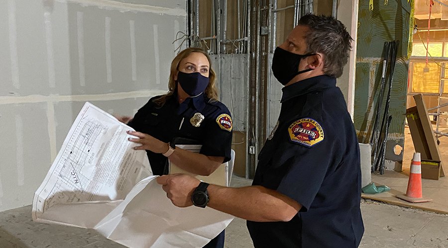 Two fire personnel doing fire inspections inside new building.