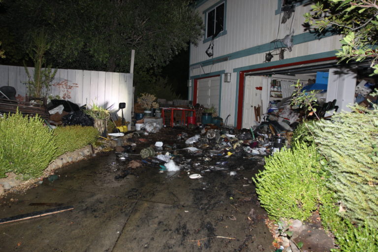 Contents strewn along wet driveway following fire attack in residential home